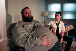 Charlie (Scott Greer) and unexpected visitor Elder Thomas (Trevor William Fayle) in Theatre Exile's THE WHALE by Samuel D. Hunter. Photo credit: Paola Nogueras.