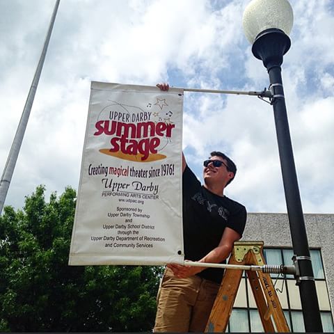 Chris Luner, Summer Stage production manager, hanging up a banner